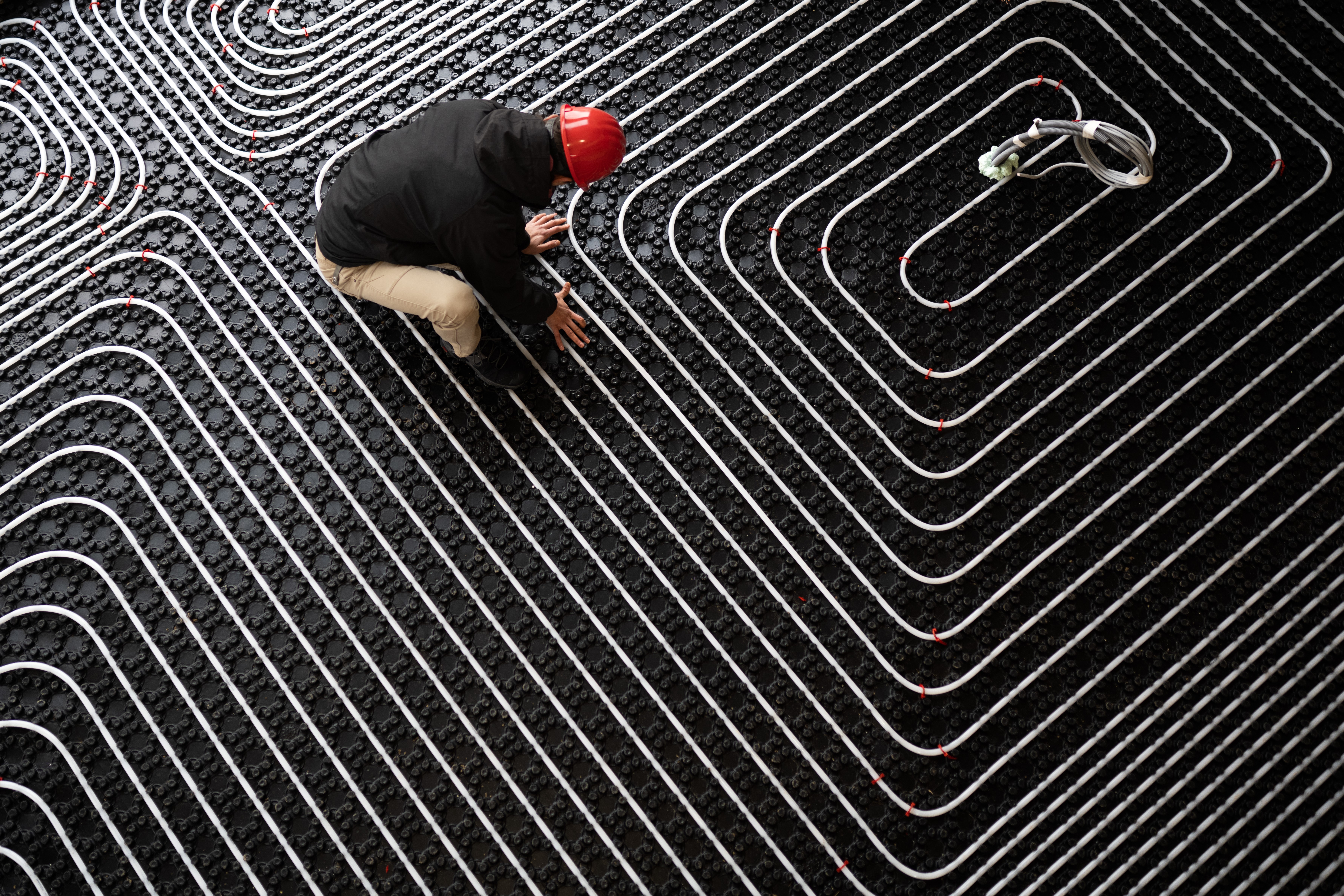 Worker adjusting position of pipes, diagonally oriented pattern on tubes